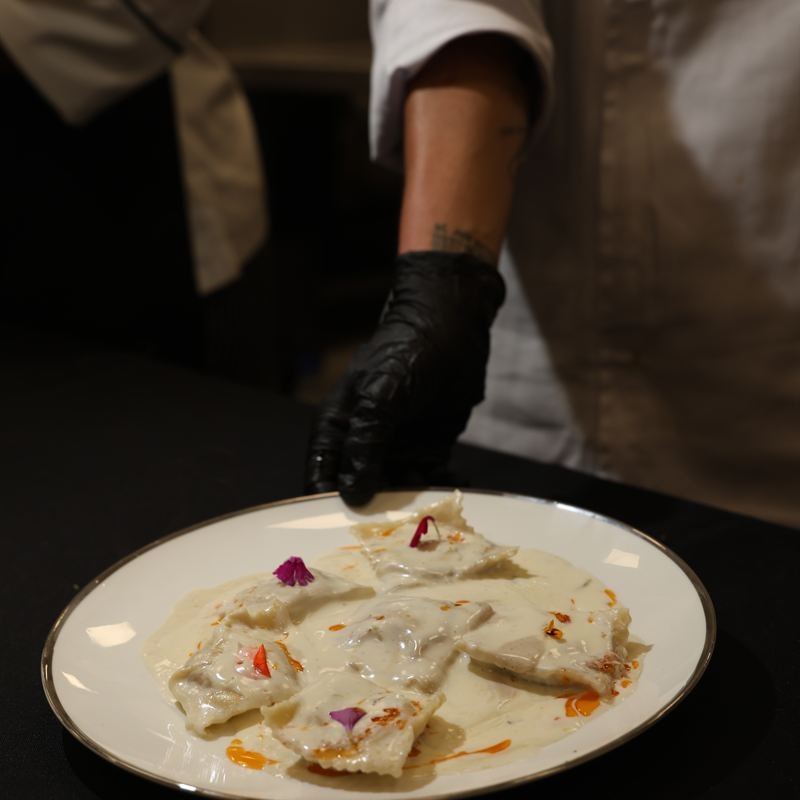 Chef terminando un plato principal con guantes negros